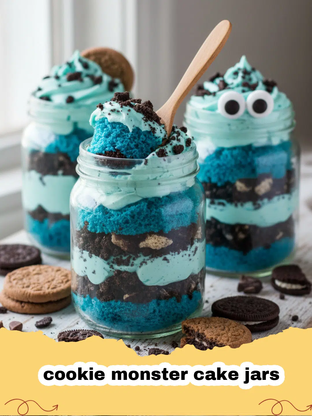 cookie monster cake jars - Close-up of a whimsical cookie monster cake jar, showing layers of blue cake, white frosting, and chocolate chip cookie chunks, with edible googly eyes on top.