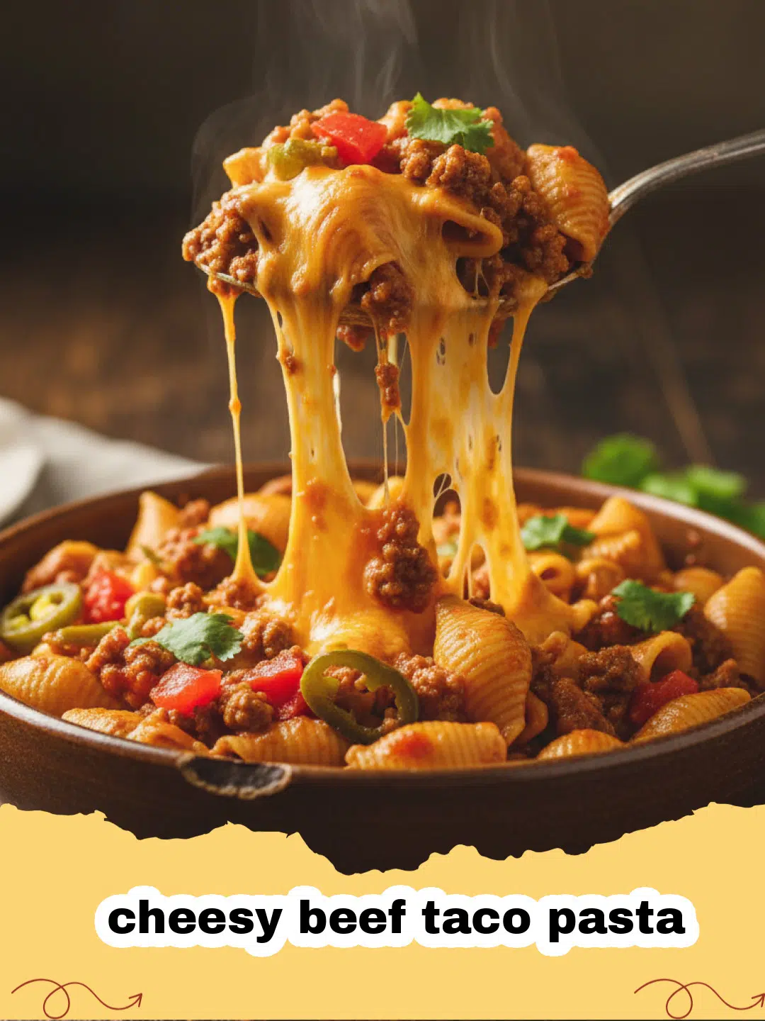 A close-up of a cheesy beef taco pasta dish garnished with cilantro and a dollop of sour cream, served in a large skillet.