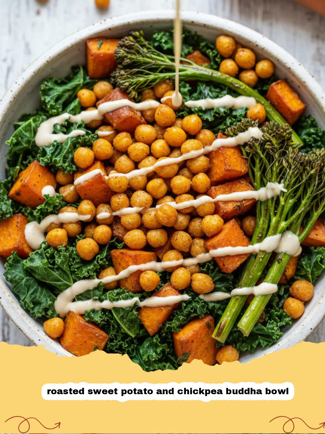 A colorful roasted sweet potato and chickpea buddha bowl with green kale and creamy dressing.