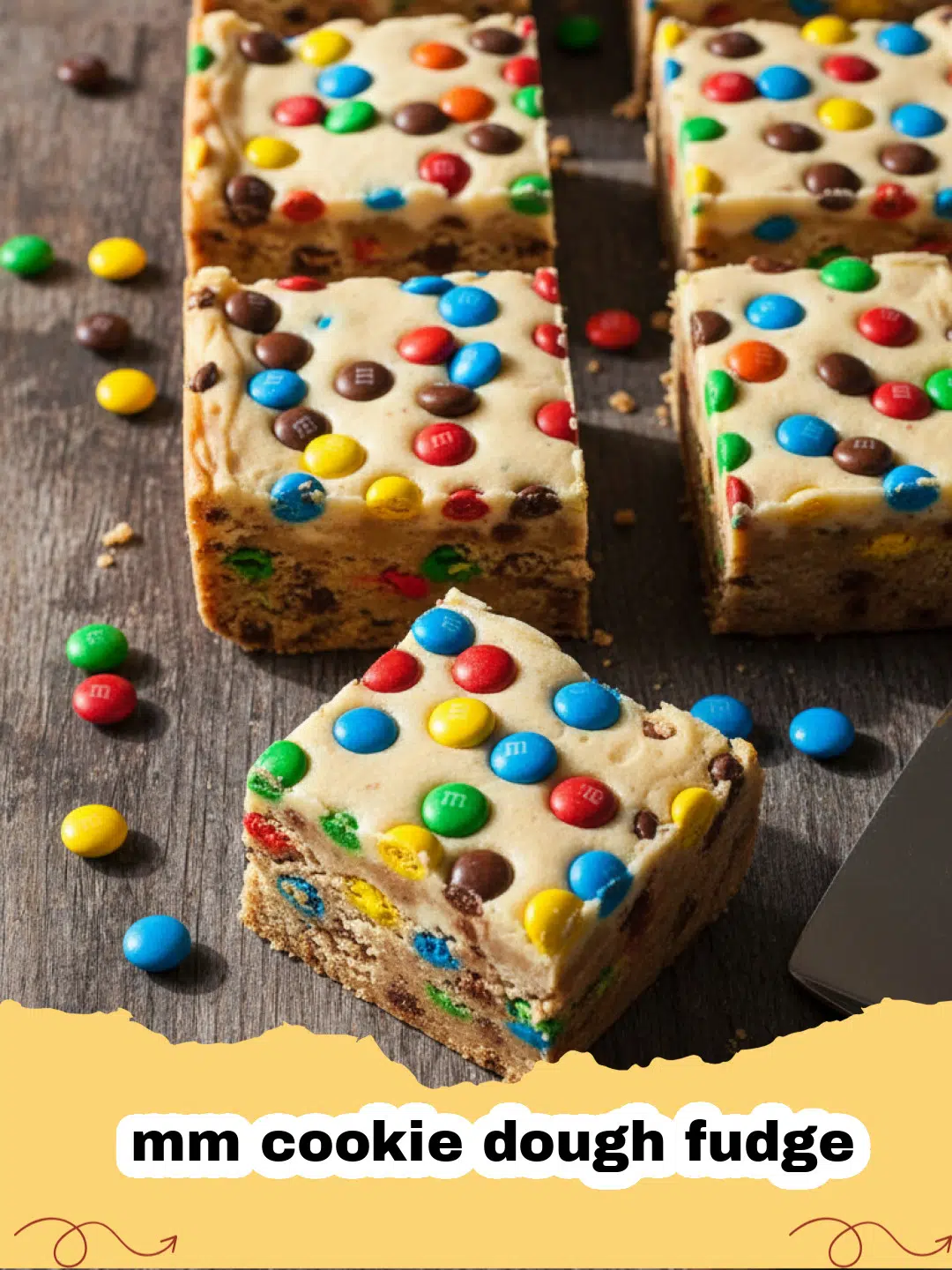mm cookie dough fudge - Close-up of colorful M&M Cookie Dough Fudge squares in a parchment-lined pan, topped with extra M&M's.