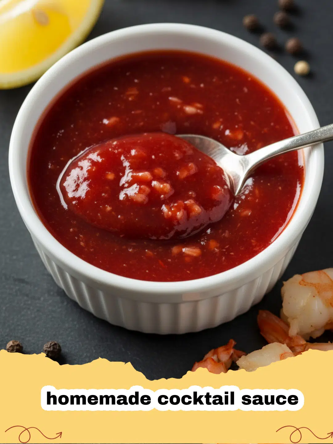 A bowl of vibrant red homemade cocktail sauce surrounded by cooked shrimp and lemon wedges.