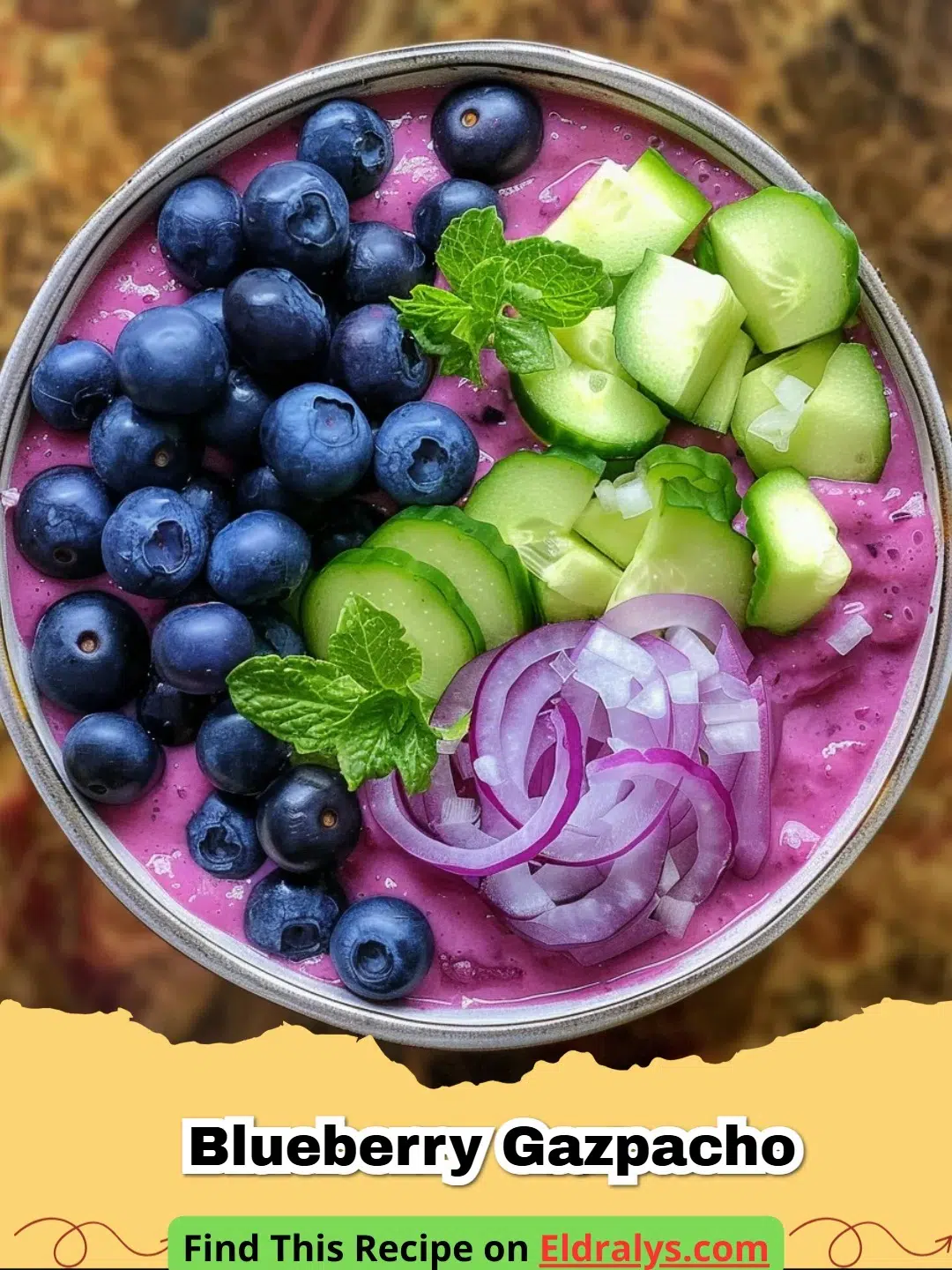 A bowl of deep purple Blueberry Gazpacho topped with mint and red onion.