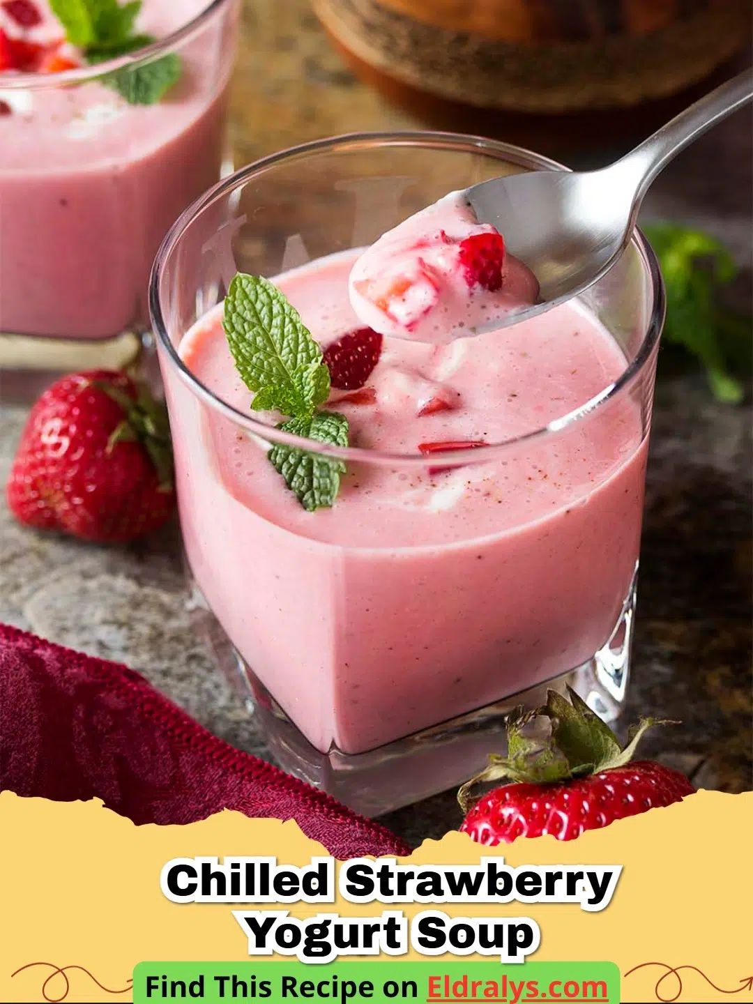 A bowl of vibrant pink Chilled Strawberry Yogurt Soup topped with mint and berries.