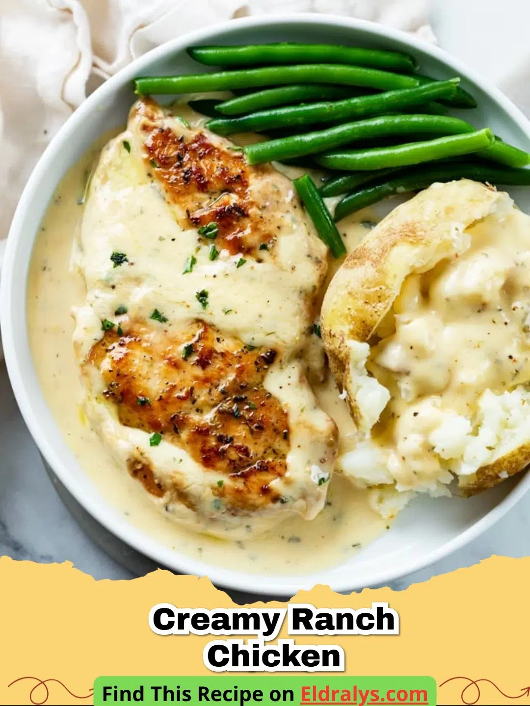 A close up shot of Creamy Ranch Chicken in a black skillet with a rich white sauce and green garnishes.
