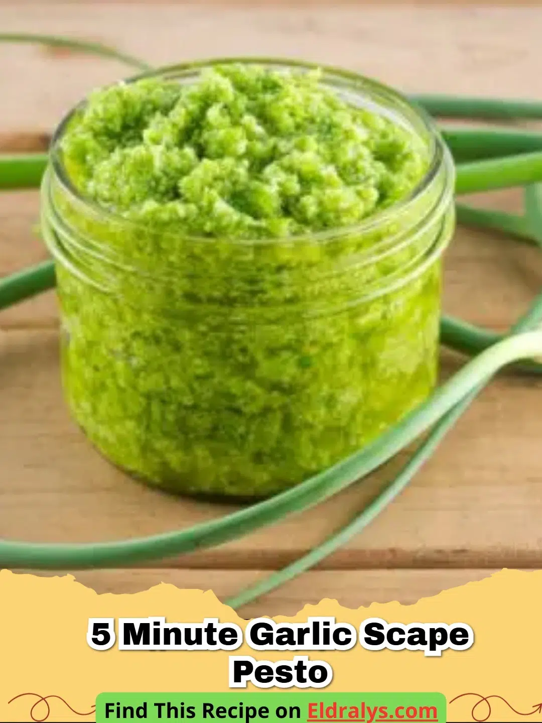 A jar of vibrant green 5 Minute Garlic Scape Pesto sitting on a rustic wooden table next to fresh scapes.