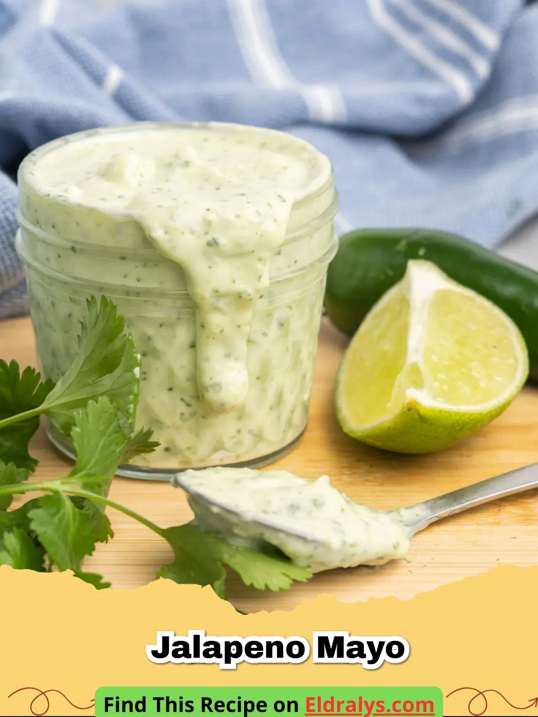 A glass jar filled with creamy light green Jalapeno Mayo surrounded by fresh peppers.