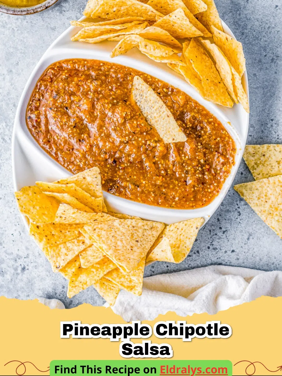 A close-up shot of fresh Pineapple Chipotle Salsa in a glass bowl with chips.