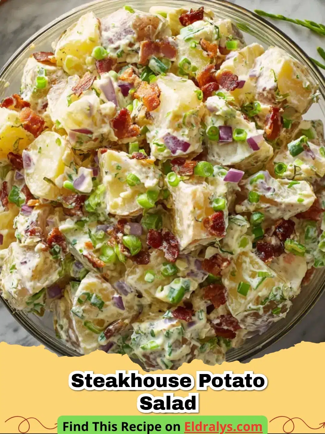 A large bowl of creamy Steakhouse Potato Salad garnished with bacon and chives.